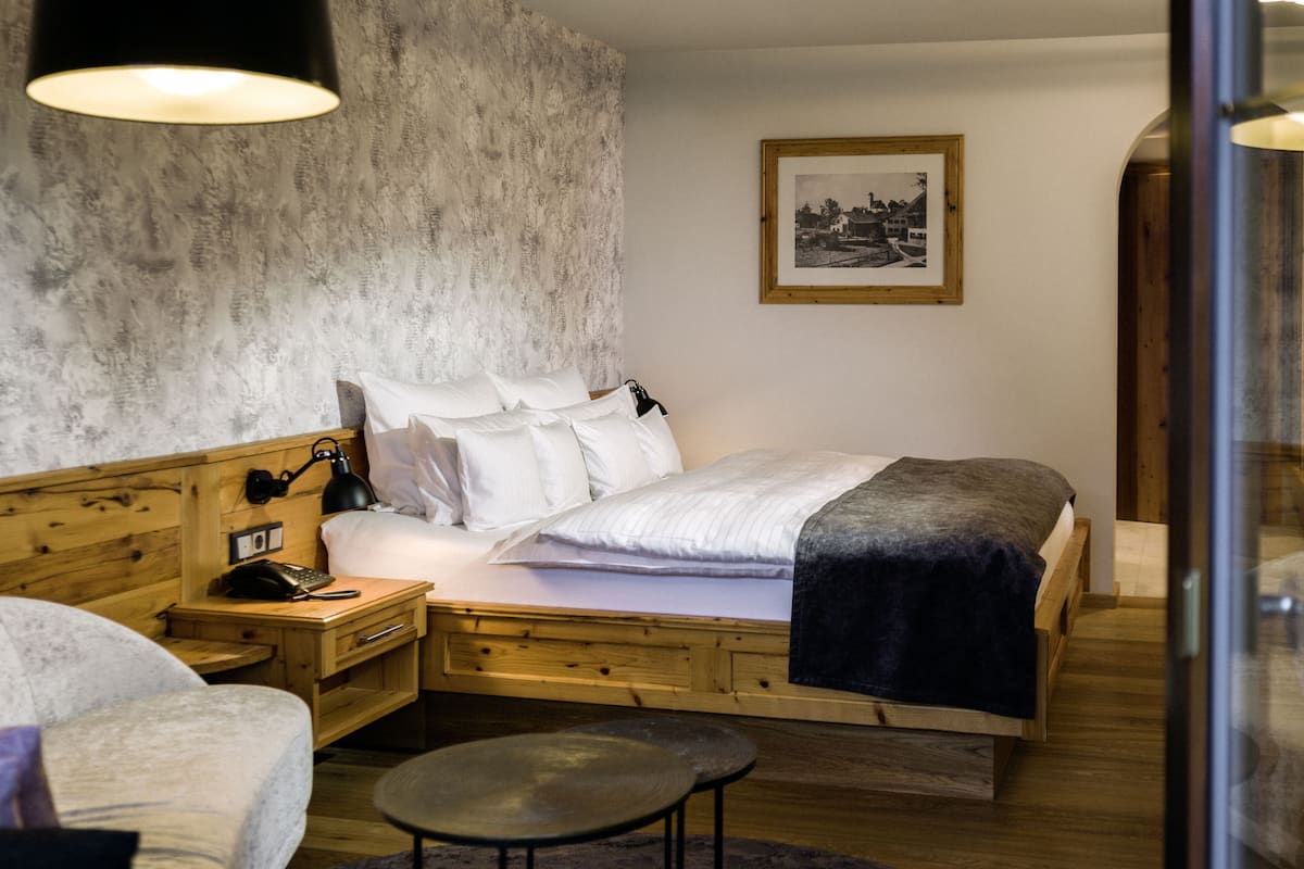 Une chambre à coucher avec un lit en bois, une table de chevet, un bureau et une chaise.