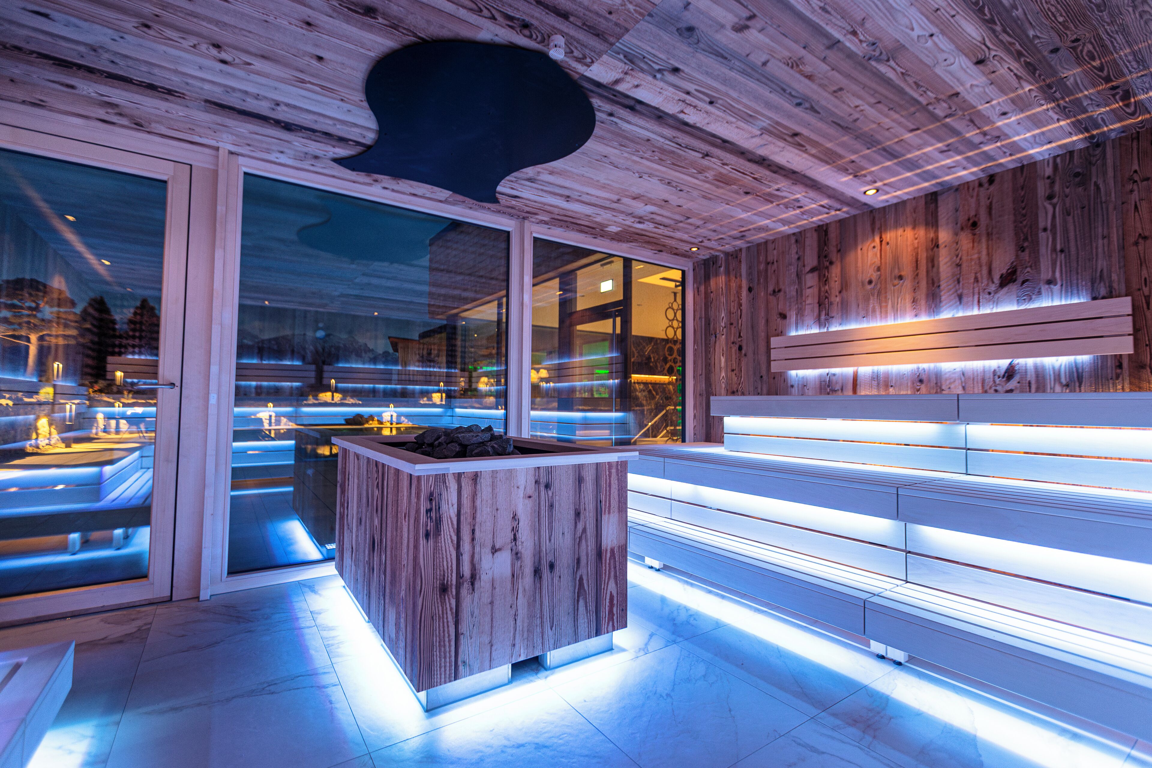 Ein modernes Interieur mit Holzvertäfelung, einer zentralen Sitzecke mit integriertem Sitzbänkchen und einer Glastür, die nach draußen führt.