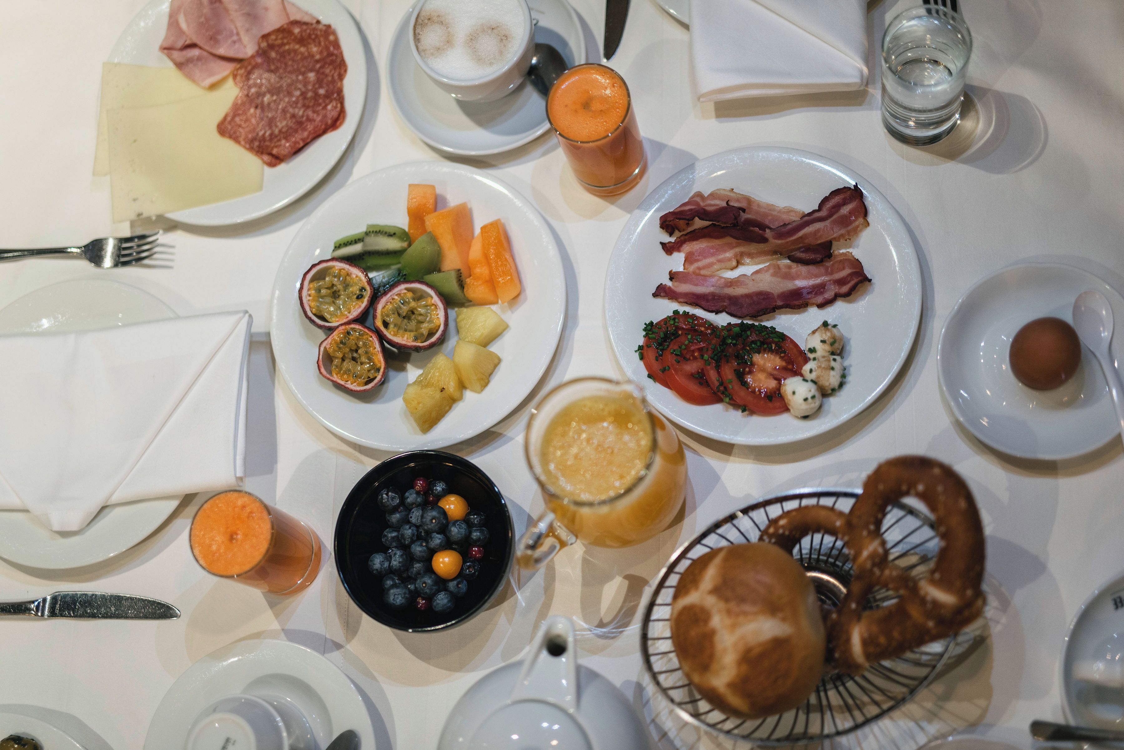 A breakfast setting with plates of food, a coffee cup, and a jug of juice.