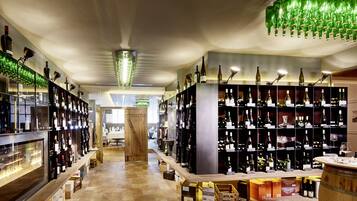 A wine cellar with shelves of wine bottles, wooden barrels, and a central wooden column.