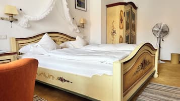 A hotel room with a bed, a chair, a wardrobe, a bedside table, a lamp, a picture on the wall, and a floor lamp.