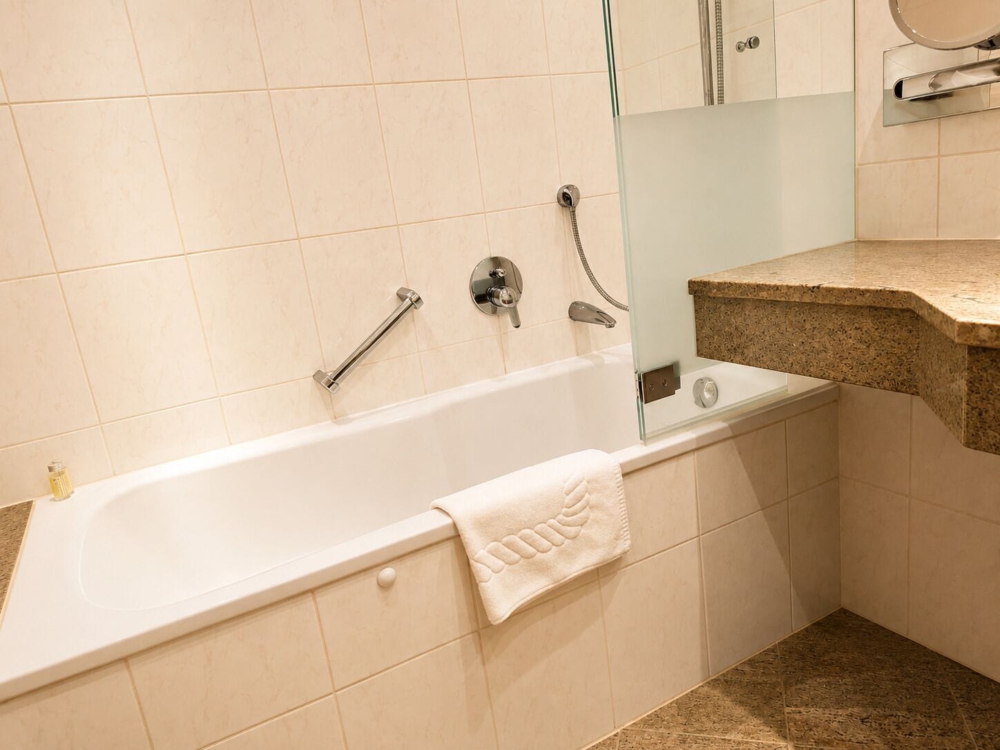 A bathroom with a bathtub, a glass shower enclosure, and a granite countertop.