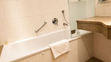 A bathroom with a bathtub, a glass shower enclosure, and a granite countertop.