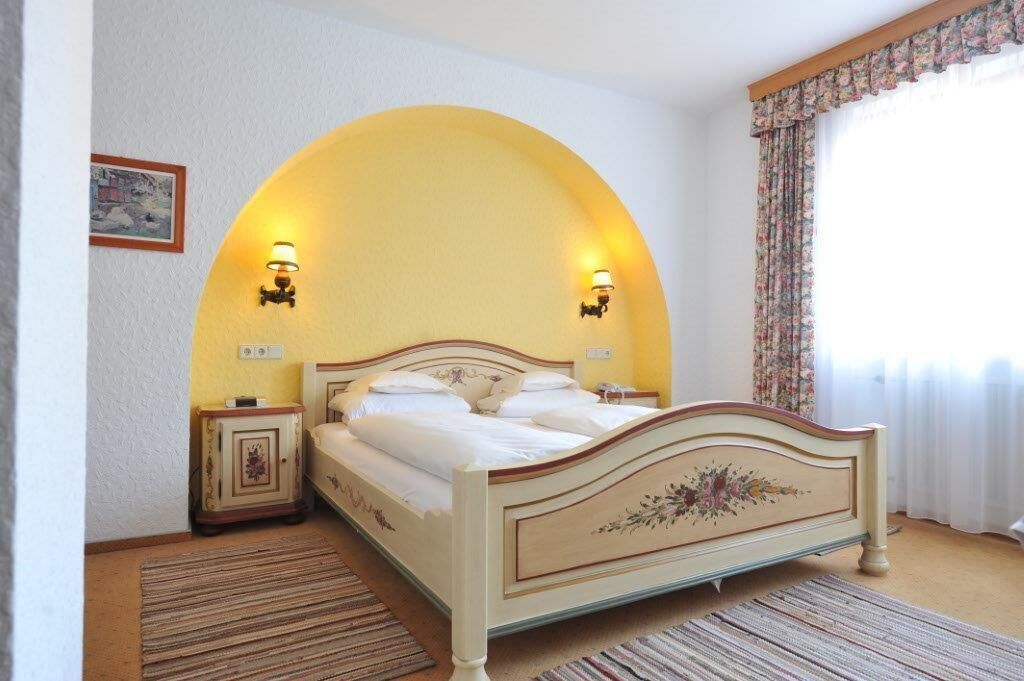 Ein Schlafzimmer mit einem Bett, zwei Nachttischen, einem Teppich und einem Fenster mit Vorhängen.