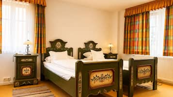 A traditional room with a double bed, two bedside tables with lamps, a patterned rug, and curtains.