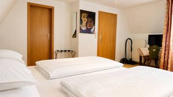 Habitación de hotel con dos camas, un escritorio, una silla, un aspirador y un cuadro en la pared.