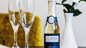 Una botella de Hotel Royal Stuttgärt Chardonnay Brut con dos copas de vino sobre una mesa.