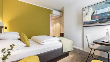 Une chambre d’hôtel équipée d’un lit, d’un bureau, d’une chaise et d’un téléviseur affichant les services proposés par l’hôtel.