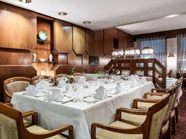 A dining area with a long table set for a meal, surrounded by wooden chairs.