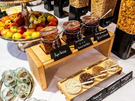 A food display with various jars of preserves and a tray of granola.