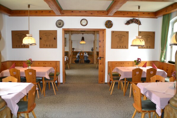 A restaurant with wooden booths and tables, a wooden ceiling, and a view into the dining area. - Hotel Gasthof Zur Linde (Rothenburg ob der Tauber)