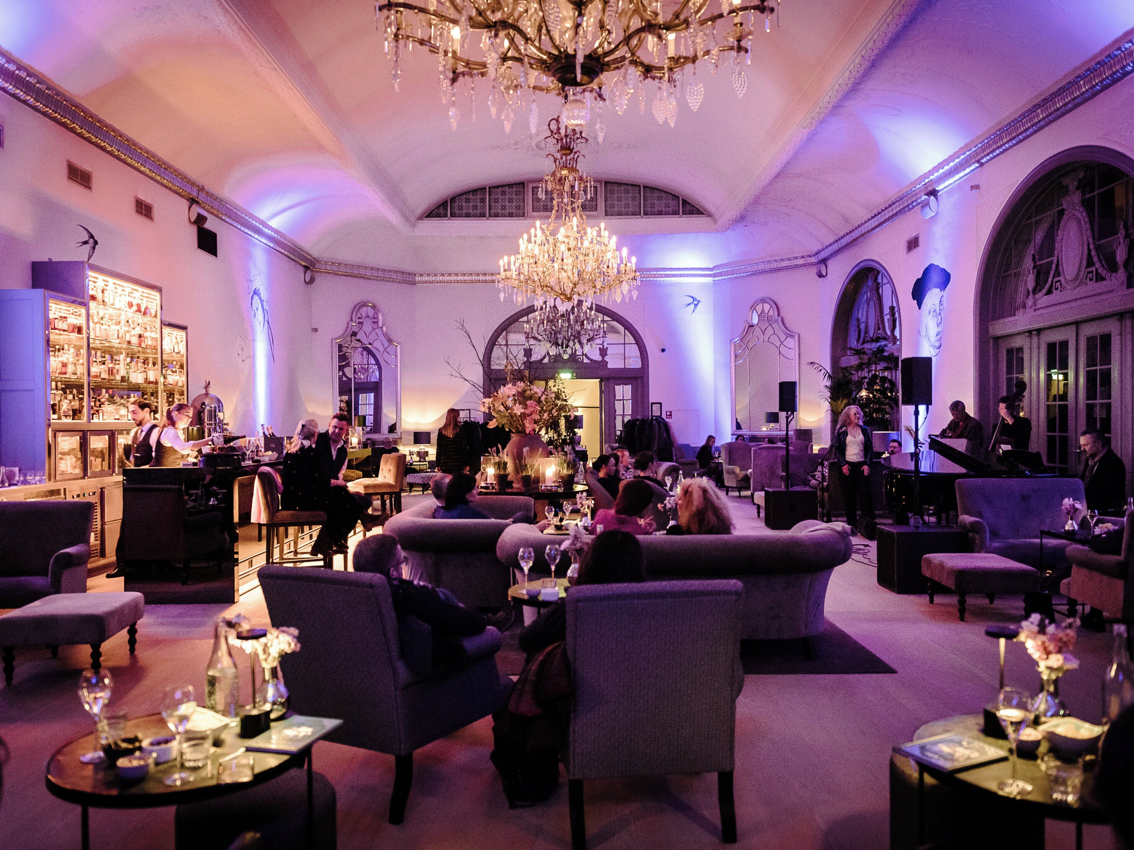 Eine großzügige Lobby mit einem prächtigen Kronleuchter, bequemen Sitzbereichen und einer Bar mit einer gut sortierten Spirituosenauswahl.
