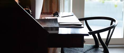 A room with a desk, chair, lamp, and a view through a window.