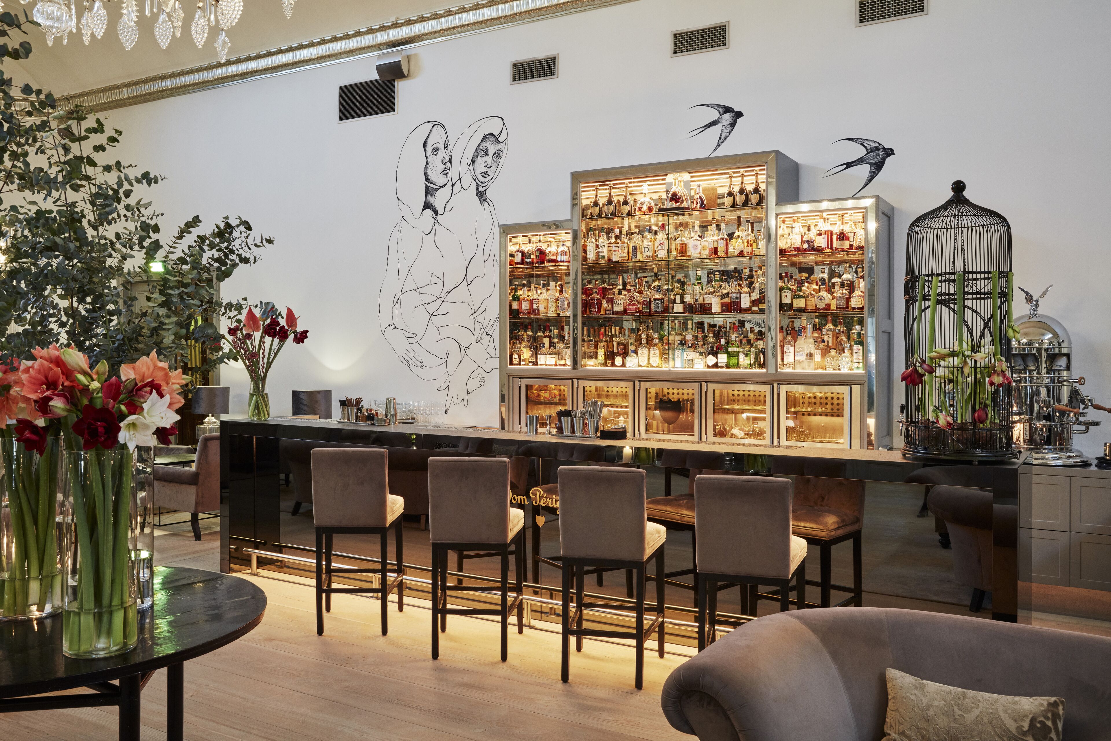 Zona de bar con barra, asientos y una vitrina iluminada llena de botellas.