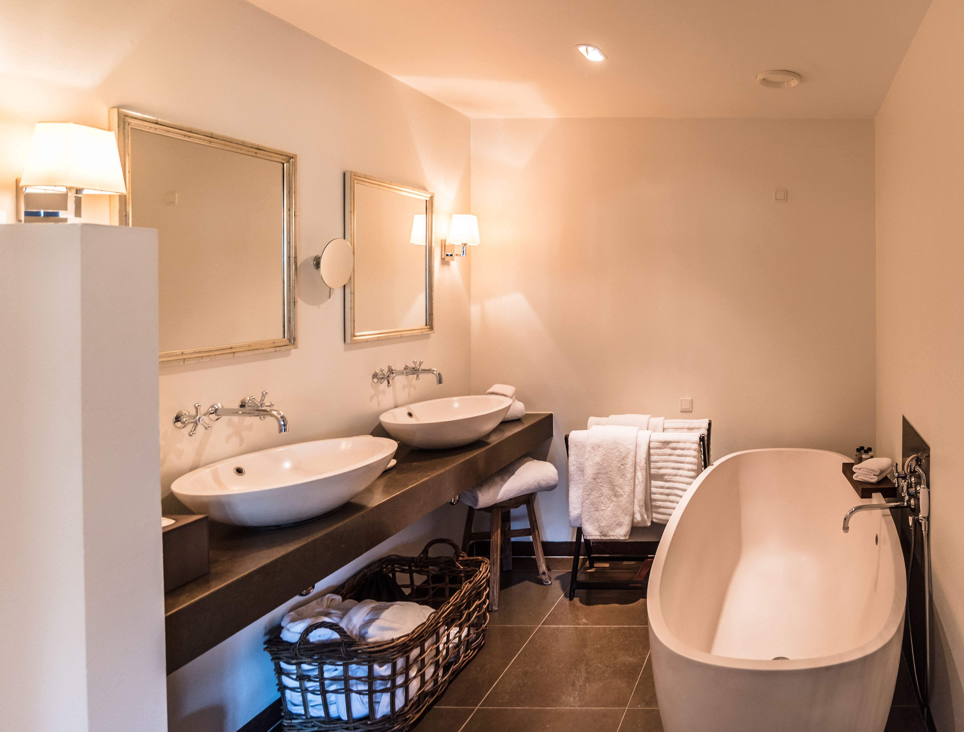 A modern bathroom with two sinks, a large bathtub, and a vanity with a mirror.