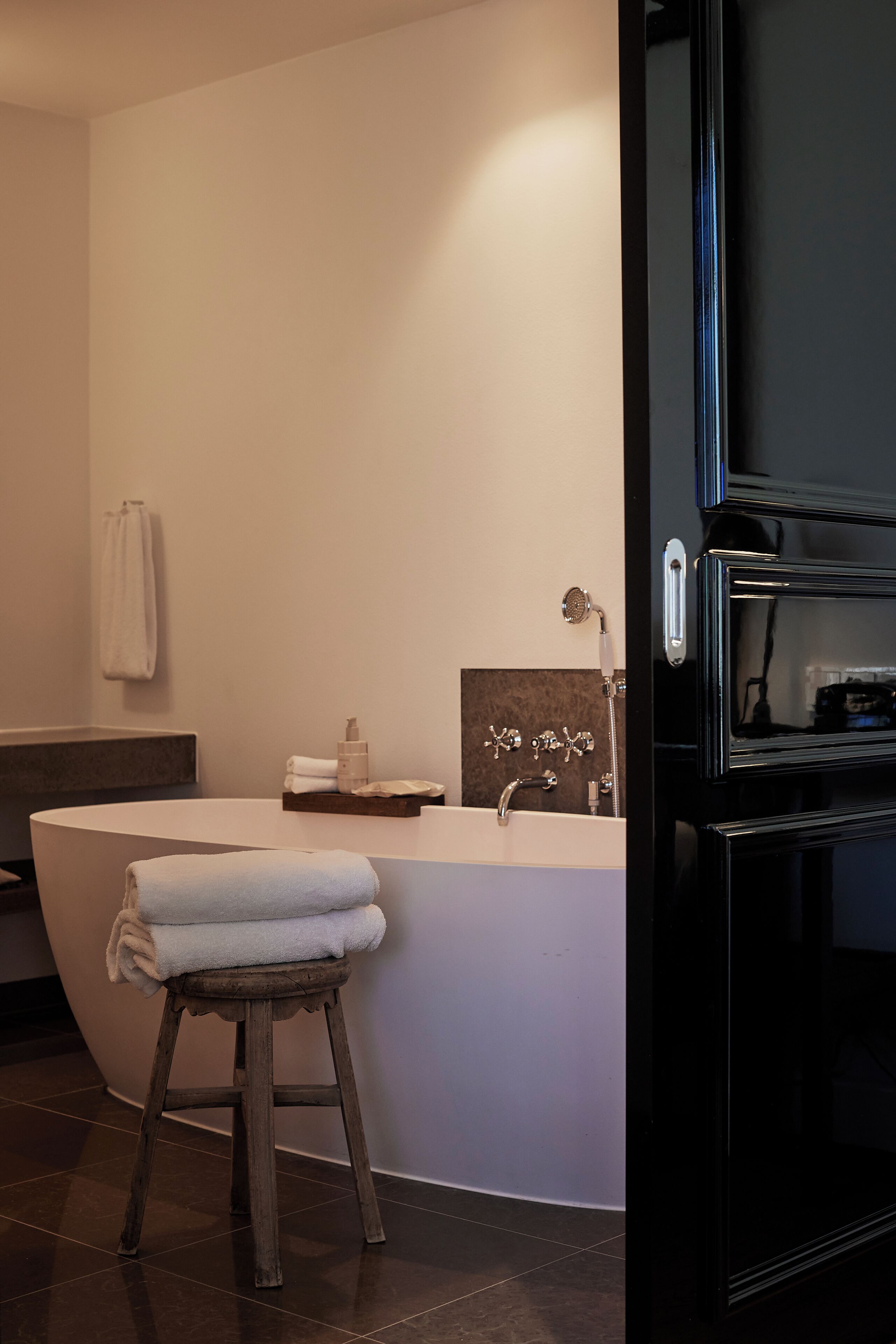 A modern bathroom with a freestanding bathtub, a vanity with a mirror, and a towel rack on the wall.