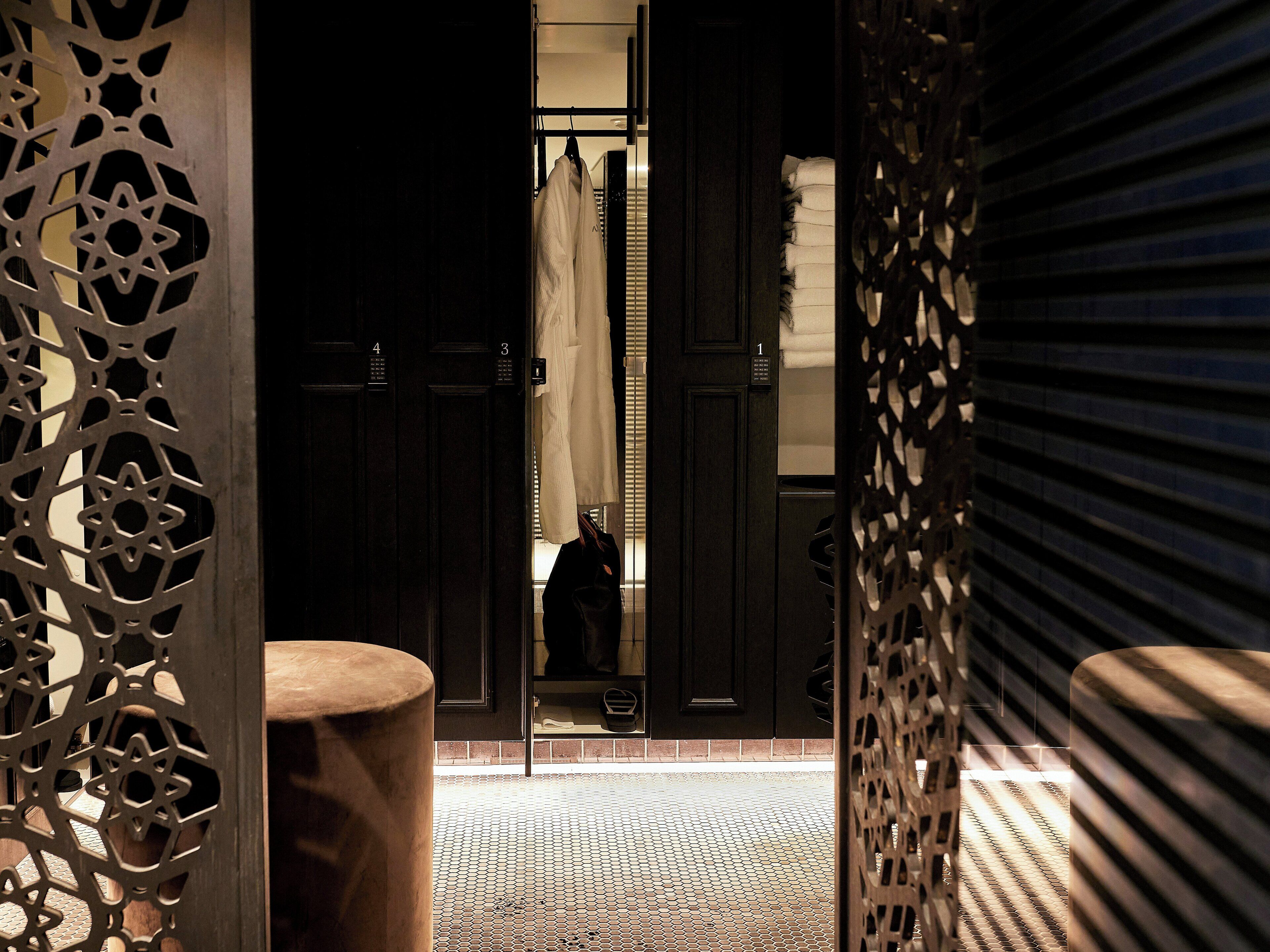 A hotel entrance with a patterned floor, a wooden bench, and a door with a number.