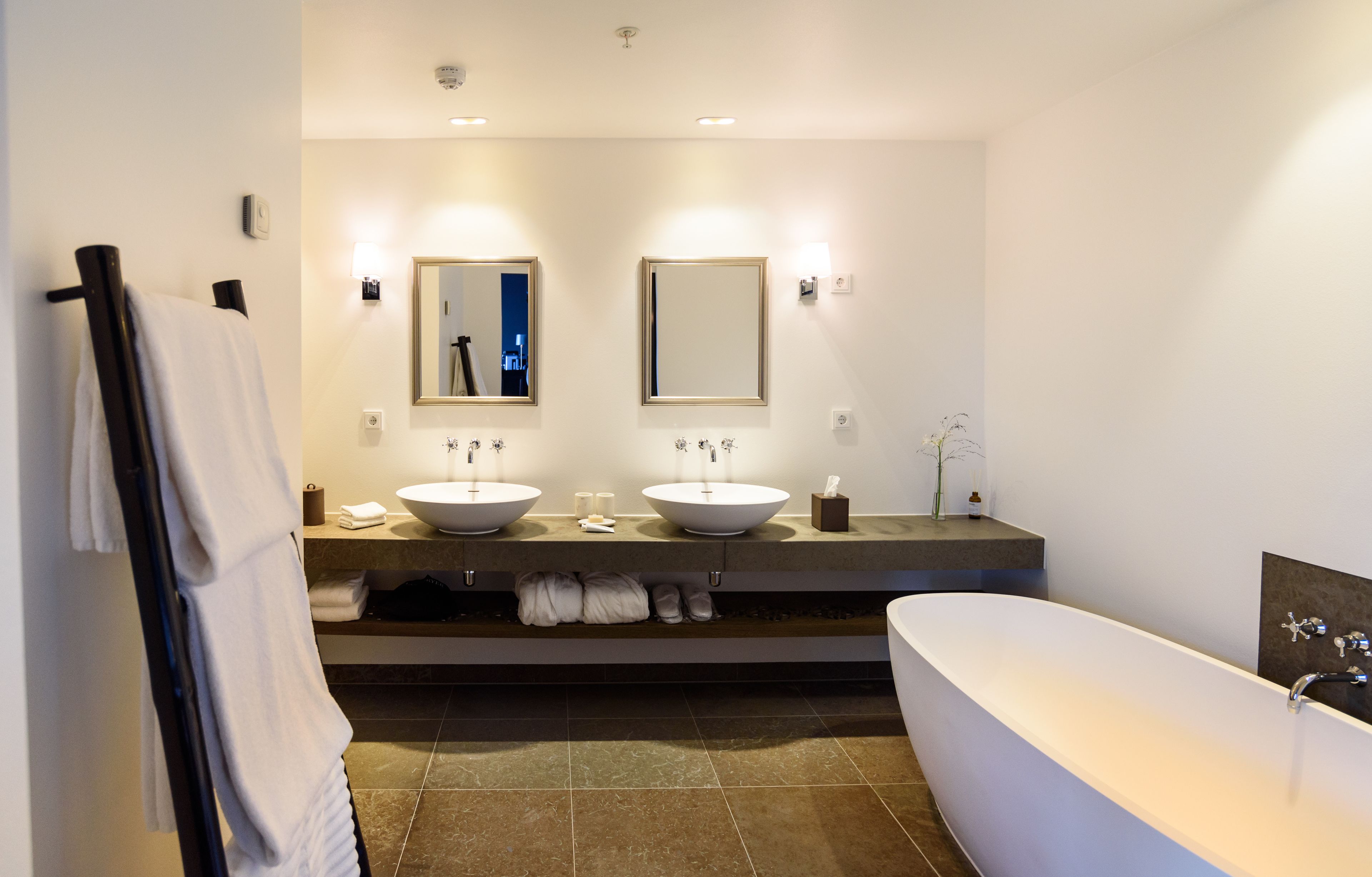 Une salle de bain moderne avec deux lavabos, une grande baignoire et un porte-serviettes.