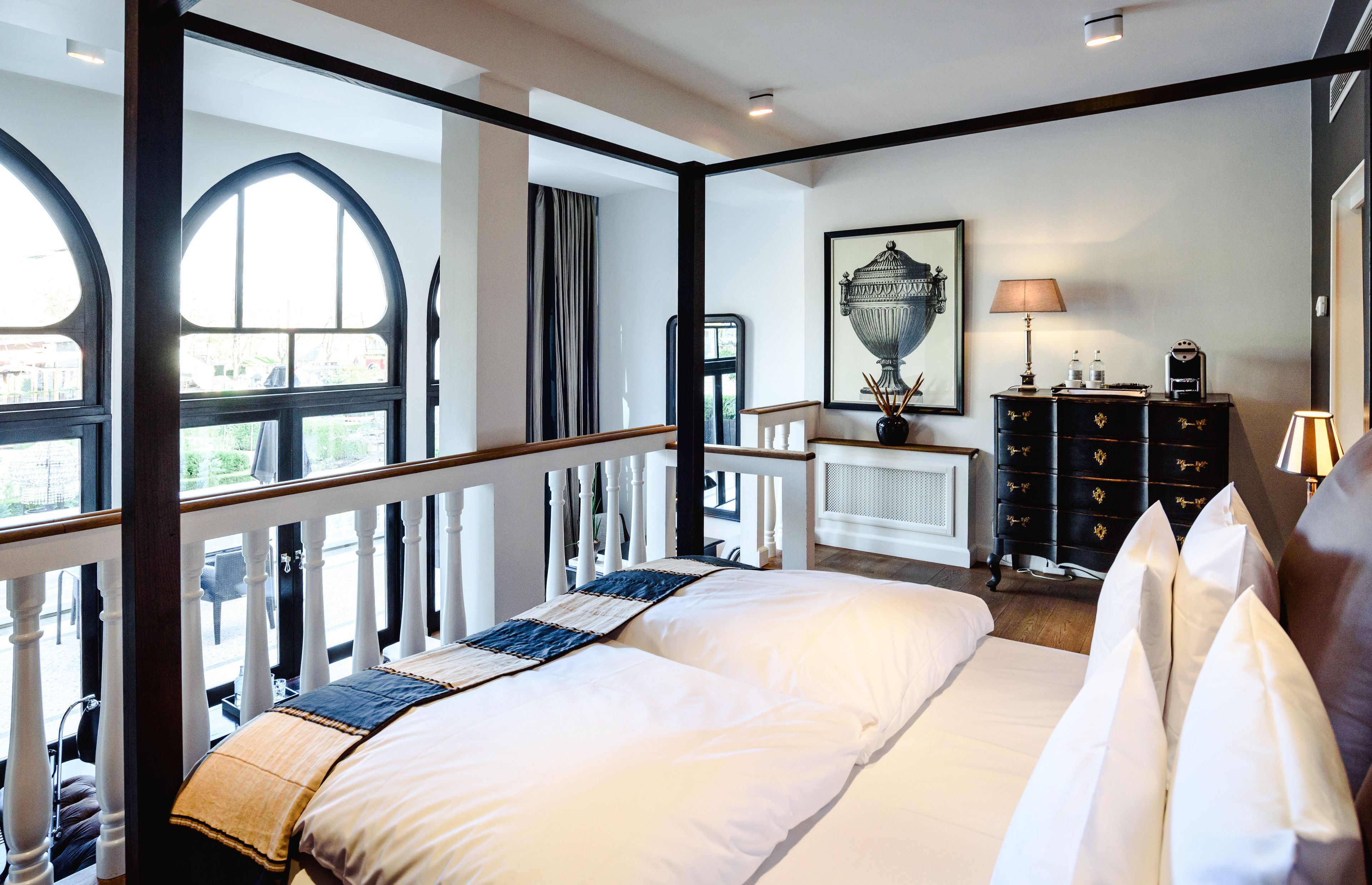 Un dormitorio con una cama grande, un aparador, un espejo y una ventana con cortinas.
