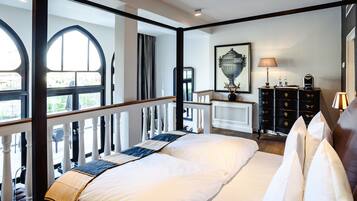 Un dormitorio con una cama grande, un aparador, un espejo y una ventana con cortinas.