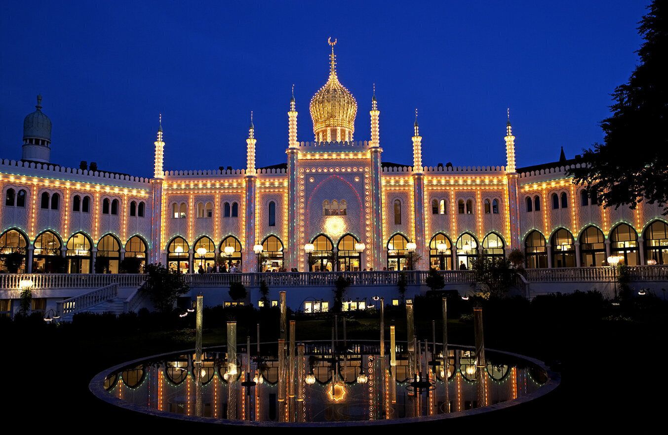 En storslagen byggnad med en central kupol och flera minareter, omgiven av en spegelblank damm.
