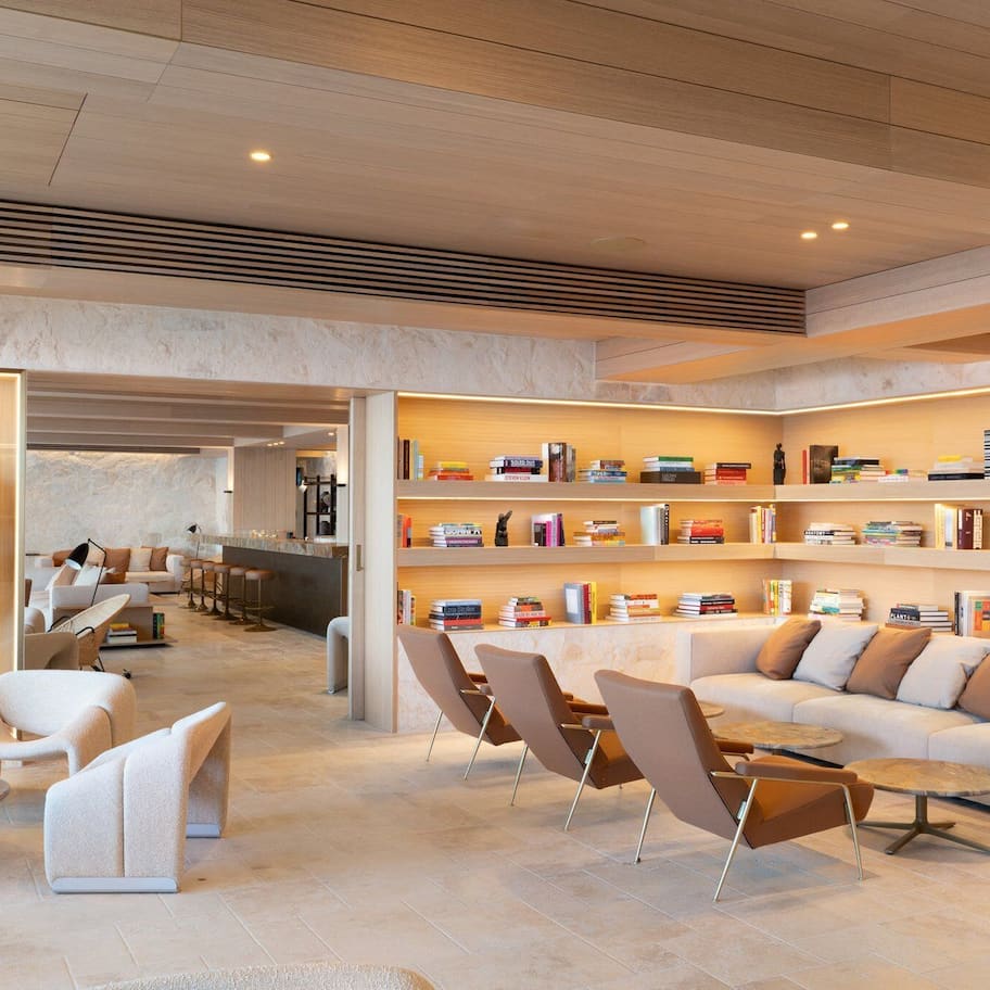 A modern lobby with a central seating area, a mannequin in a red outfit, and bookshelves with various books.