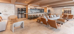 A spacious living area with a bar, seating arrangements, and a stone wall backdrop.