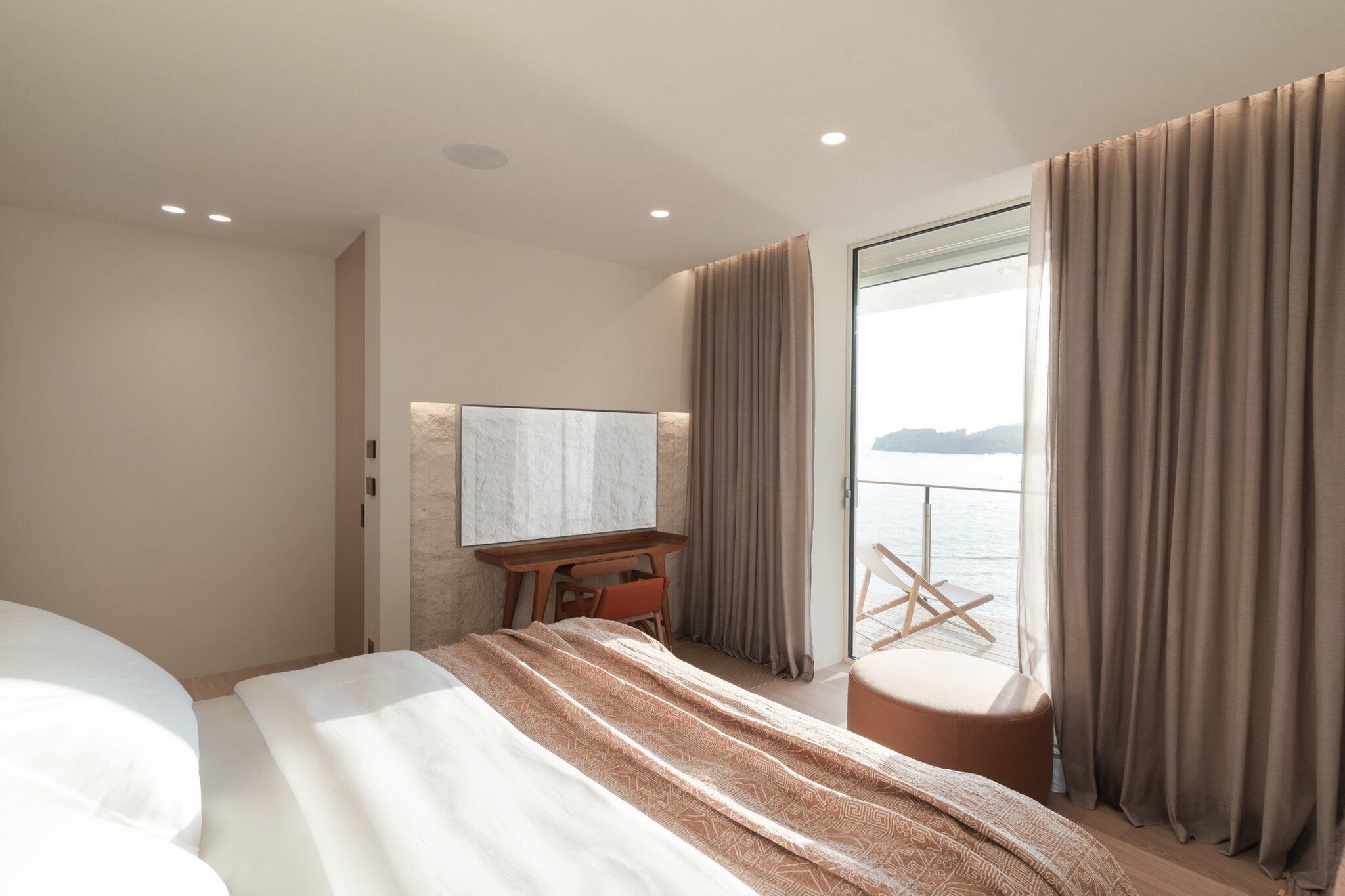 Et moderne hotelværelse med en stor seng, et skrivebord og havudsigt.