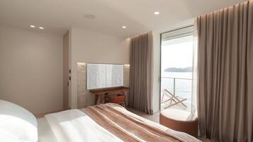 Et moderne hotelværelse med en stor seng, et skrivebord og havudsigt.