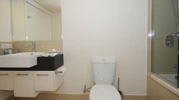 A bathroom with a white toilet, a sink with a black countertop, and a glass shower enclosure.