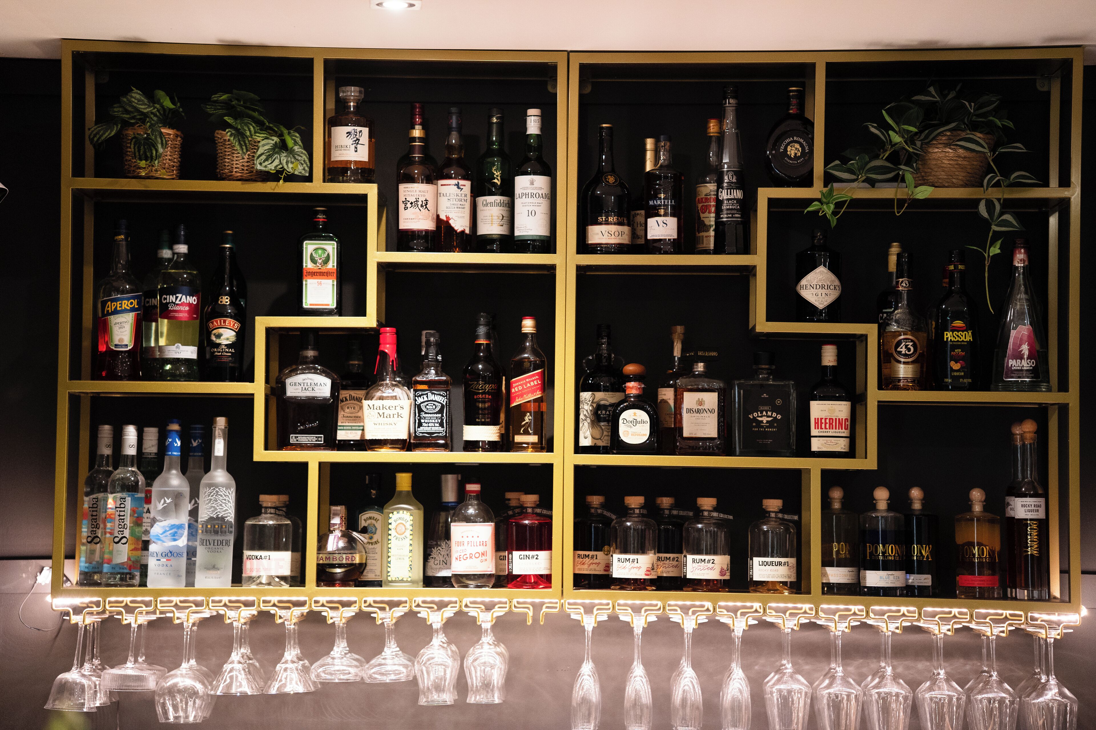 Zona de bar con estantes llenos de botellas de licor y vasos.