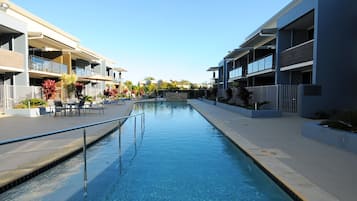 Una piscina al aire libre, sombrillas, sillones reclinables de piscina