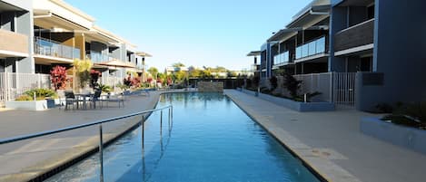 Una piscina al aire libre, sombrillas, sillones reclinables de piscina