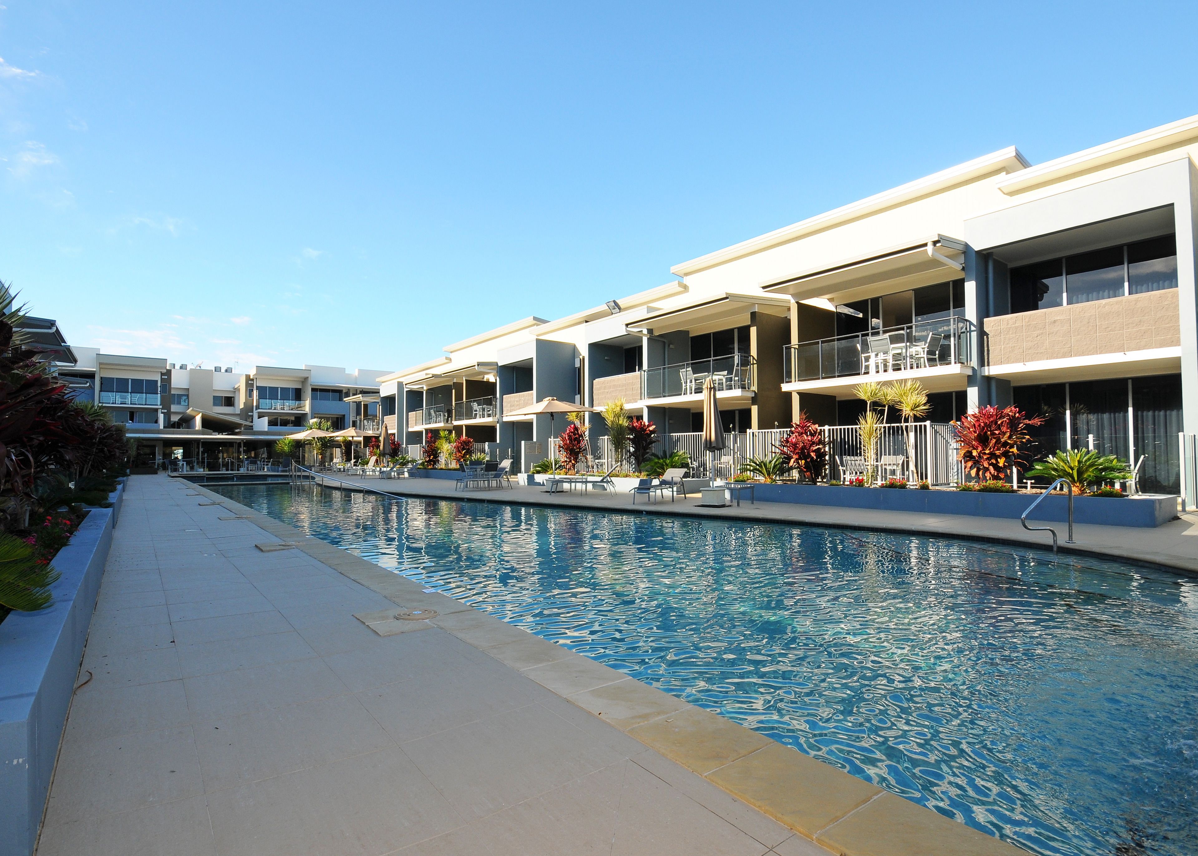 Ein modernes Hotel mit Schwimmbad, Sitzgelegenheiten im Freien und Balkonen.
