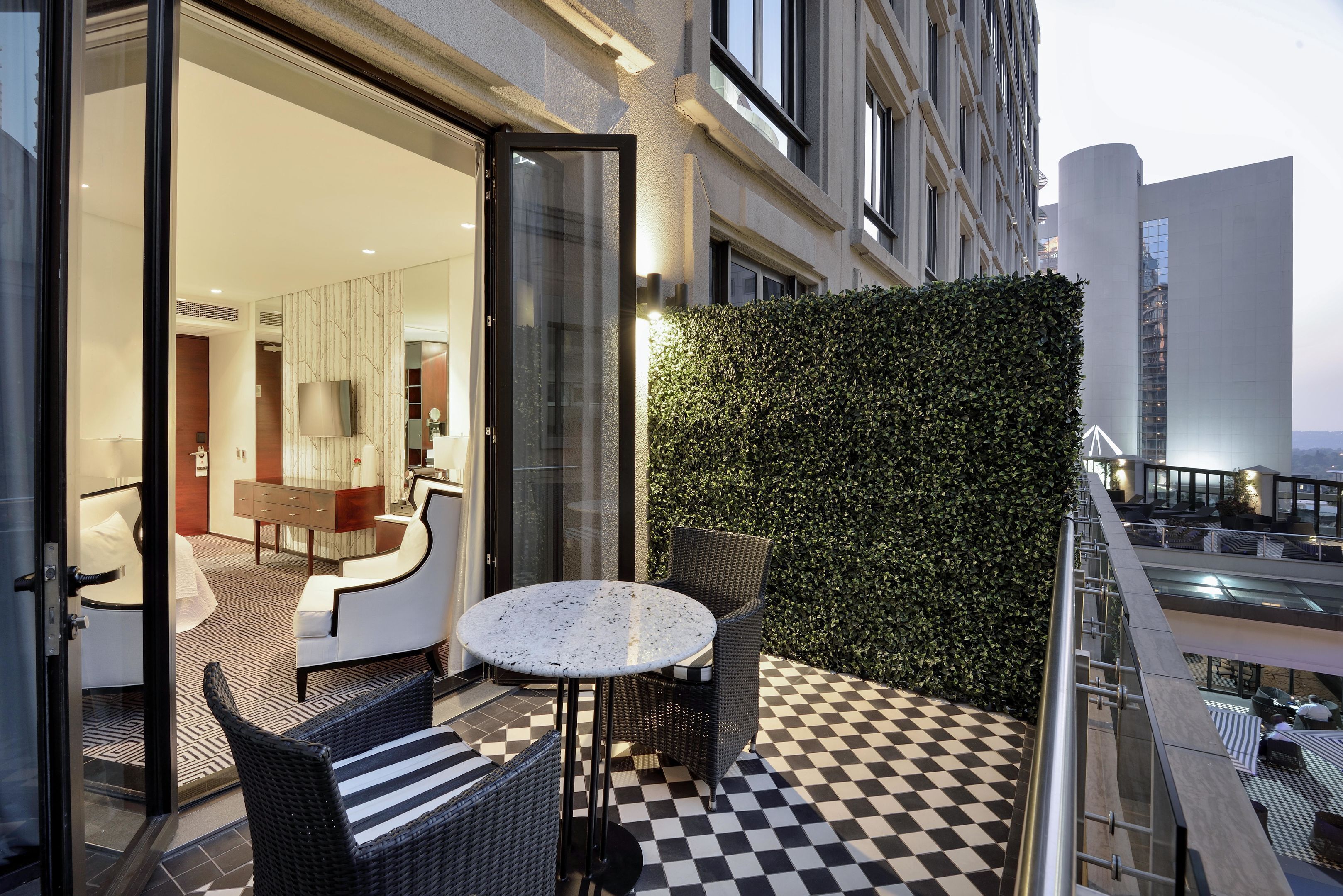 A modern outdoor seating area with a checkered floor, a round table, and wicker chairs.