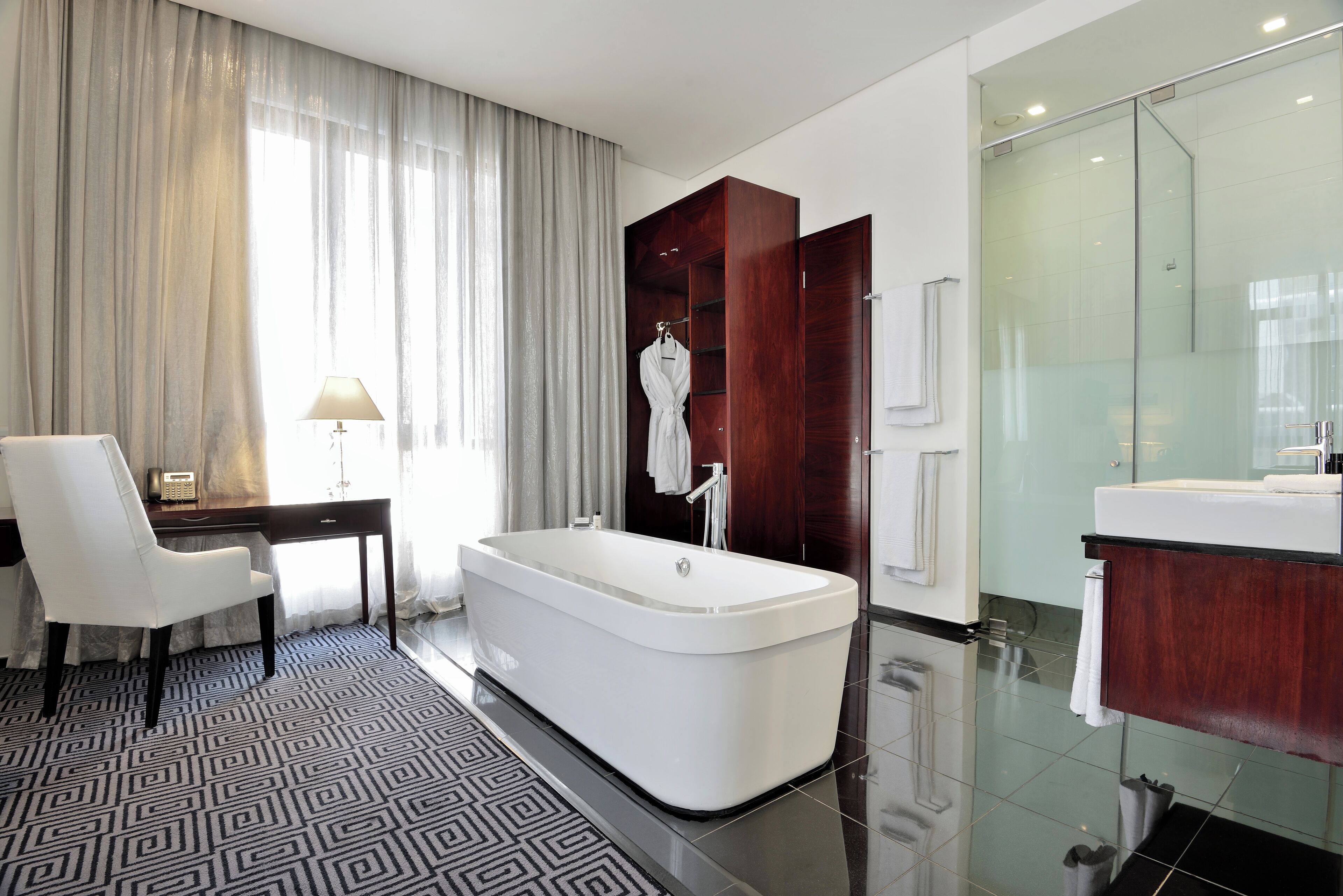 Un baño moderno con una bañera independiente, un tocador con espejo y un box de ducha de vidrio.