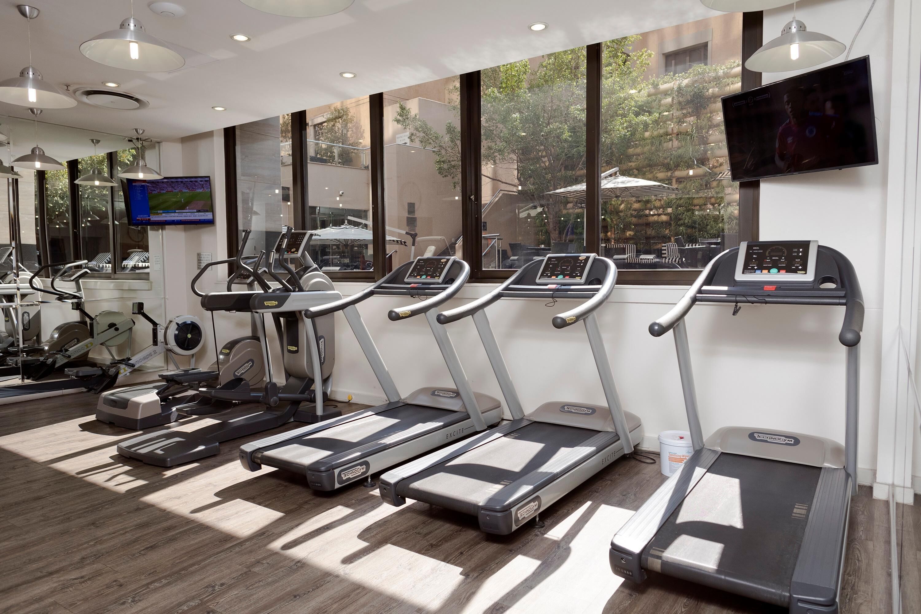 Un gimnasio con cintas de correr, elípticas y una pantalla de televisión.
