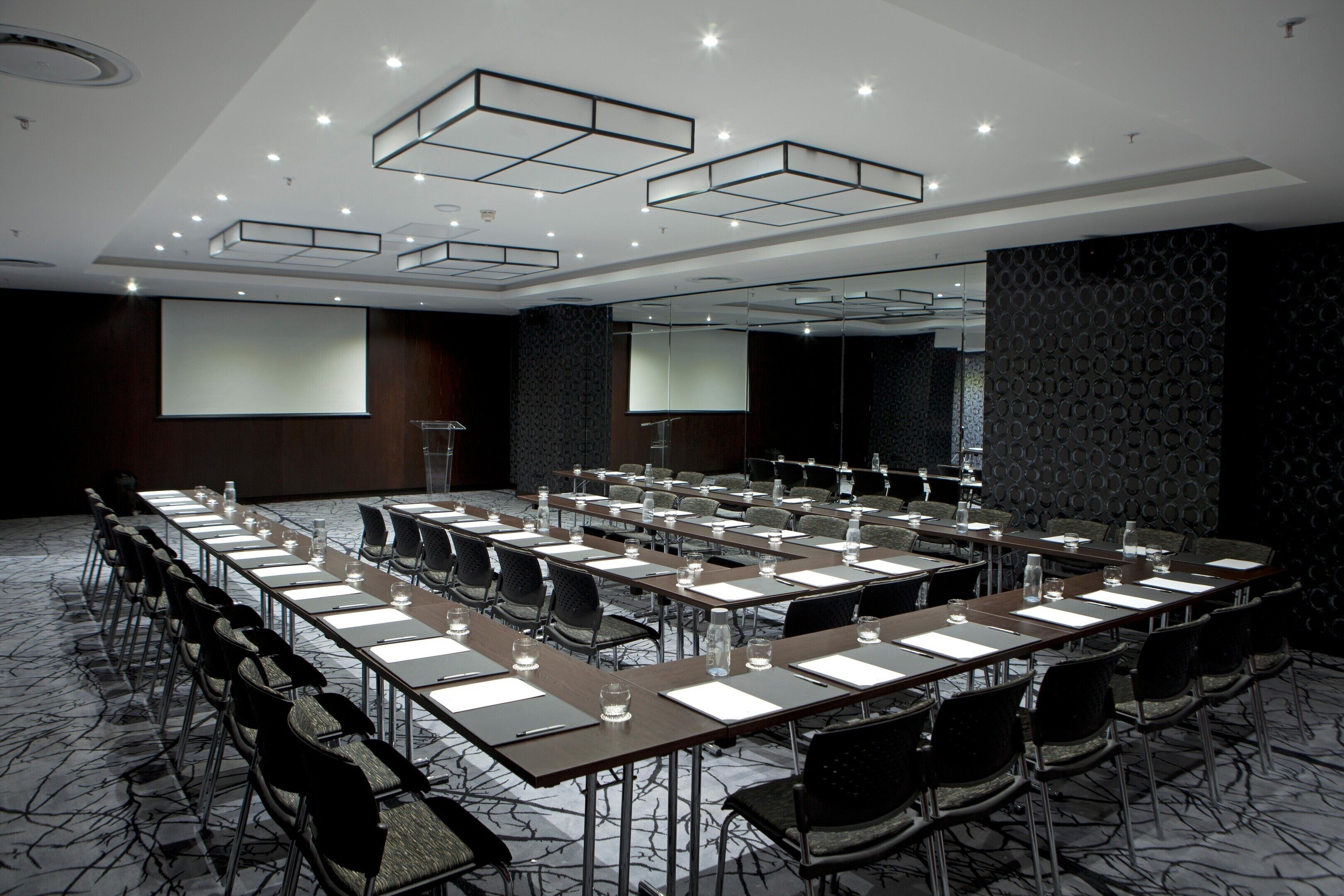 A conference room with a long table, chairs, and a projector screen.