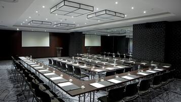 A conference room with a long table, chairs, and a projector screen.