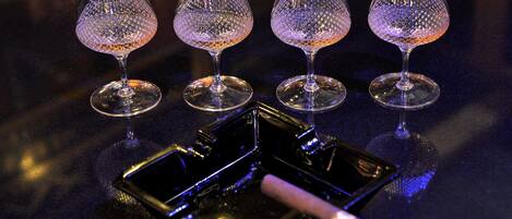 Three clear glass wine glasses on a dark surface with a tray and a smartphone.
