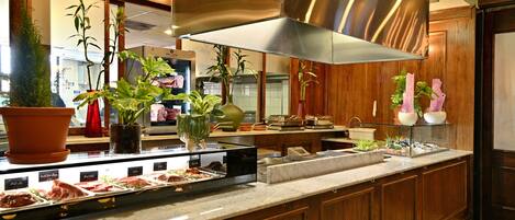 A well-lit kitchen with wooden cabinets, stainless steel appliances, and a variety of fresh produce and meats displayed on the counter.