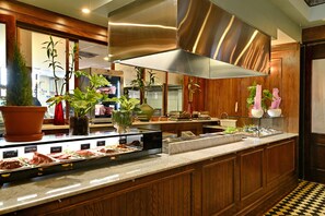 Cocina bien iluminada con gabinetes de madera, electrodomésticos de acero inoxidable y una variedad de frutas y carnes frescas exhibidas en la encimera.