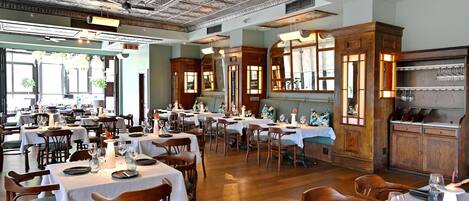 A restaurant with multiple dining tables, chairs, and a bar area.