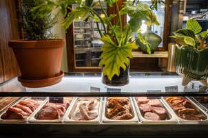 Vitrina de carnes con diferentes cortes y una planta en primer plano.