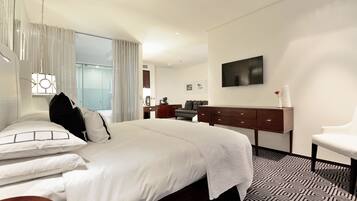 Una habitación de hotel moderna con una cama grande, un escritorio, una silla y un televisor en la pared.