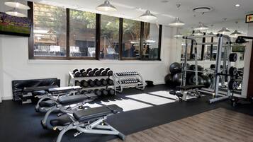 A gym with exercise equipment, dumbbells, and a bench.