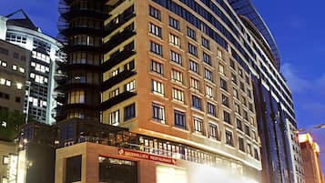 A multi-story hotel with a curved facade, large windows, and a restaurant on the ground floor.
