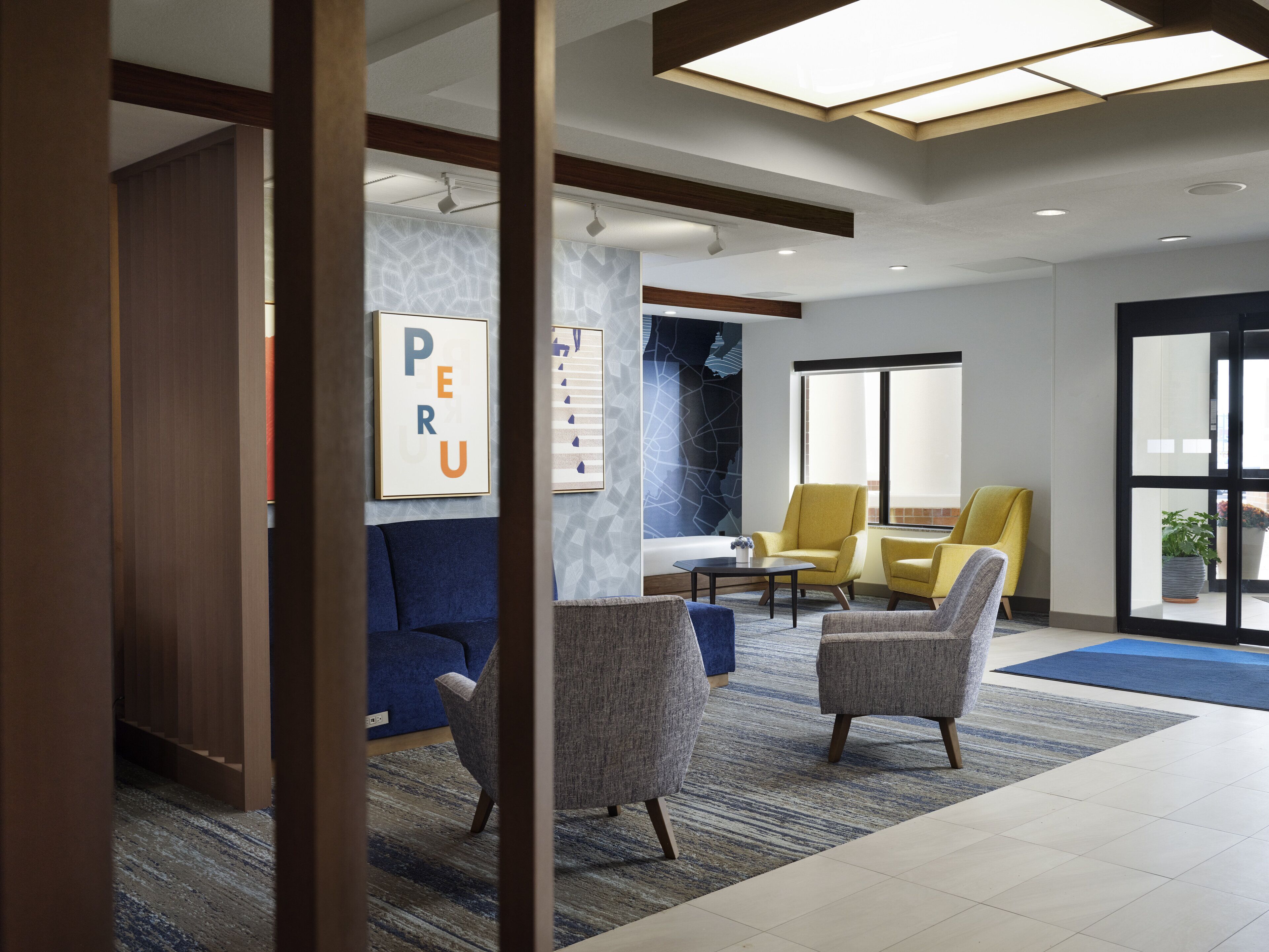A modern lobby with a blue sofa, two armchairs, a coffee table, and a large window.