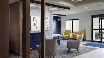 A modern lobby with a blue sofa, two armchairs, a coffee table, and a large window.