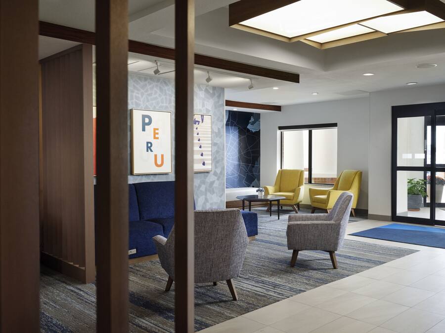 A modern lobby with a blue sofa, two armchairs, a coffee table, and a large window.